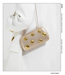 Detail of champagne gold evening clutch bag with pebble-shaped metal accents and chain