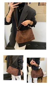 Macro view of dark brown suede handbag with golden hardware and adjustable strap