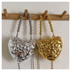 Detail of silver and gold heart acrylic clutches with hammered liquid metal texture