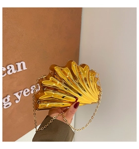 Close-up of luxury gold shell-shaped evening bag with metallic texture and chain strap