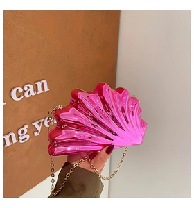Detail of shell-shaped bright pink metallic evening bag with gold chain strap