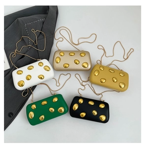 Flat lay of colorful textured evening clutch bags with golden pebble accents and chain straps