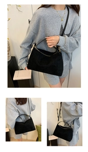 Detail of black suede crescent bag showing gold zipper and adjustable shoulder strap