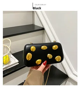 Detail of matte black PU clutch with pebble-like gold accents and fine chain strap