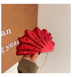Macro shot of red shell-shaped acrylic clutch bag with wave patterns and gold chain