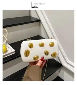 Close-up of white PU leather clutch featuring polished gold organic pebble ornaments