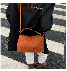 Detail of orange suede tote with textured diamond pattern shown on a city street