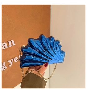 Detail of shell-shaped acrylic evening bag in blue metallic finish with gold chain strap