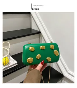 Detail of green evening clutch bag featuring artistic gold metallic accents and chain strap