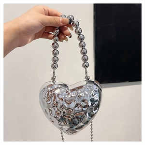 Detailed view of silver heart-shaped evening bag with textured finish and beaded handle