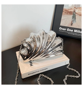 Close-up of silver shell-shaped evening clutch with metallic wavy texture and chain