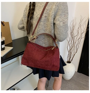 Detail of wine red suede tote bag with diamond quilted pattern and slim shoulder strap