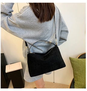 Close-up of black suede tote bag with matte texture and elegant gold hardware accents
