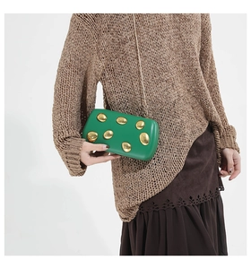 Close-up of emerald green PU leather clutch with gold pebble metal accents and chain strap
