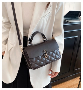 Close-up of diamond quilted stitching and golden twist lock on a vintage crossbody bag