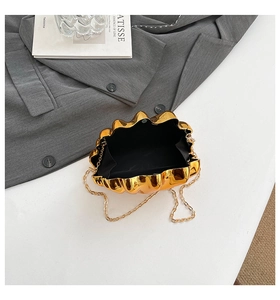 Detailed view of an open golden shell evening bag with black lining and chain strap