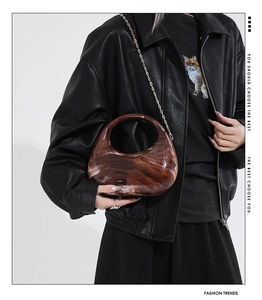 Detail of tortoiseshell acrylic crescent bag with golden chain and cutout handle