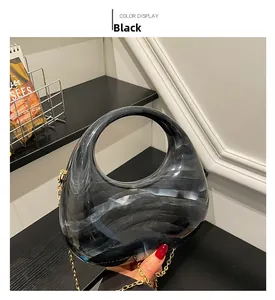 Detail of black marble acrylic handbag with minimalist curved handle and gold chain