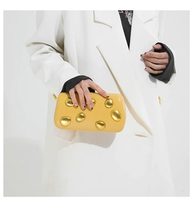 Detail of mustard yellow PU leather clutch with liquid gold metal textured accents