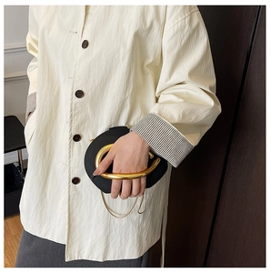 Detail of minimalist black matte clutch with bold U-shaped gold handle and metal luster