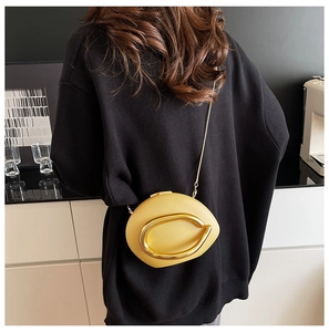 Detail of bright yellow oval clutch bag with gold metal ring and thin chain strap