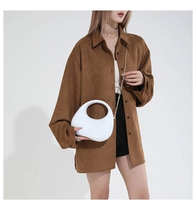 Detail of white acrylic handbag with circular handle and gold chain on brown shirt