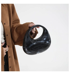 Detail of teardrop marble acrylic handbag held by a model in a luxury beige coat