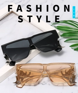 Détail de lunettes de soleil oversize avec branches en métal flamme et monture carrée
