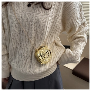 Detail of a 3D gold rose flower acrylic evening bag with a metal crossbody chain on a model