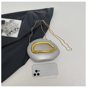Detail view of silver pebble evening bag with gold chain and handle next to phone