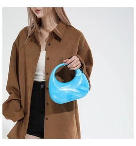 Blue acrylic crescent bag with marble texture shown held by a model for size reference