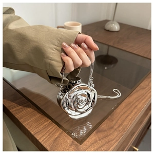 Detailed view of a silver metallic rose-shaped clutch bag with elegant chain strap