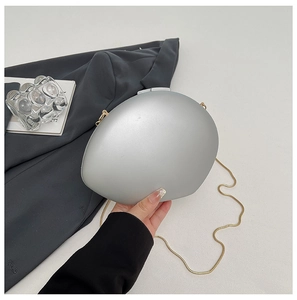 Detail of silver matte hardshell clutch with golden snake chain on a modern background