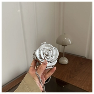 Detail of silver rose-shaped acrylic clutch with metallic petals and chain strap
