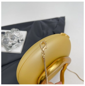 Detailed close-up of golden round evening bag with circular handle and snake chain strap