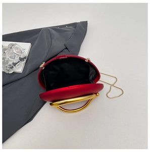 Open view of red oval hard shell evening bag with gold U-handle and chain strap