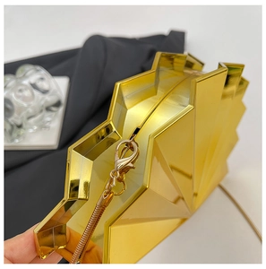 Detailed macro view of the gold fan-shaped clutch bag's metallic facets and chain