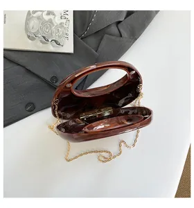 Detail of amber marble acrylic clutch bag with golden chain and elegant round handle