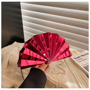 Detail of fuchsia fan-shaped evening bag with metallic finish and gold chain strap