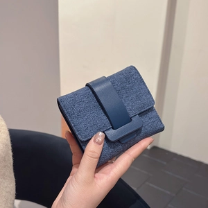 Short navy blue trifold wallet in textured denim fabric with leather clasp closure
