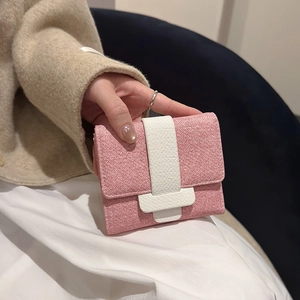 Minimalist pink and white trifold wallet with wide T-buckle held in a lifestyle setting