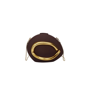 Detailed view of brown pebble-shaped evening bag with a bold gold metal arc accent