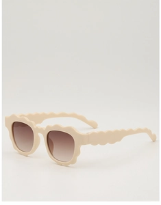 Detail of beige children's sunglasses with scalloped wavy frames and brown gradient lenses
