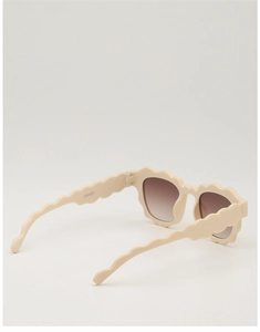 Detailed close-up of wavy beige frame children sunglasses with brown gradient lenses