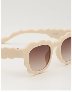 Detail of beige wave-shaped frame and brown gradient lenses on children's sunglasses