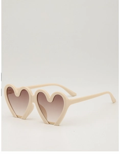 Detail view of heart-shaped beige frame sunglasses with brown gradient lenses for kids