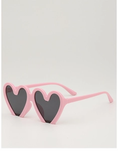 Detail of pink heart-shaped kids sunglasses with dark lenses on a neutral background