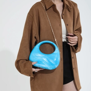 Blue marble acrylic handbag with gold chain strap shown on model for elegant styling