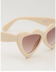 Detailaufnahme der herzförmigen Sonnenbrille mit cremefarbenem Rahmen und Verlaufsgläsern
