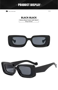 Detail view of bold black rectangle sunglasses with high-gloss frame and grey lenses